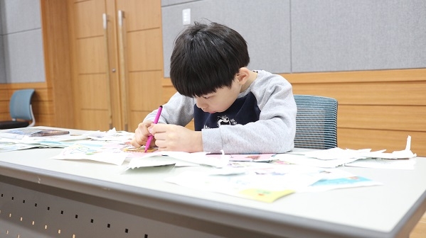 남자 장애아동이 연필을 쥐고 학습지를 풀고 있다