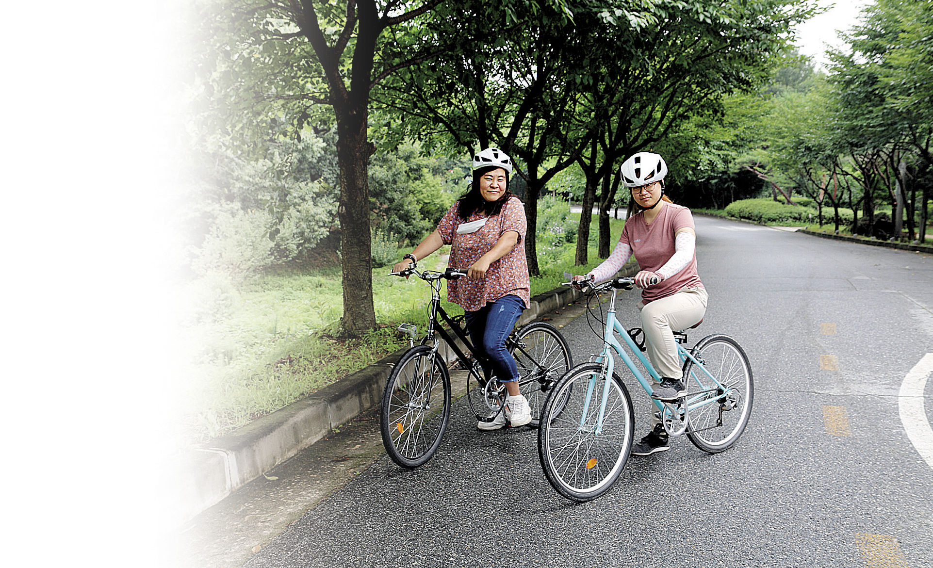 두명의 장애가족이 헬멧을 쓰고 자전거를 타고 있다.