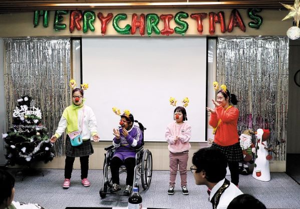 연말 파티에서 장애아동 4명이 아기상어 머리띠와 붉은 코를 붙이고 무대에서 춤을 추는 모습 