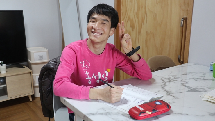 미남가수 홍성일이라는 문구가 써져있는 분홍색 티셔츠를 입고 브이를 하고 있는 홍성일 장애아동