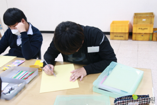 책상에 앉아 활동지를 작성하는 참가자들의 모습. 장애가족 행복지킴이 승가원 ci 삽입