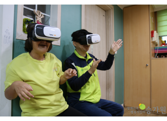 남녀 장애가족이 VR을 착용하고 손을 허우적거리며 즐거워하고 있다./오른쪽 하단에 장애가족행복지킴이 승가원 CI로고 삽입