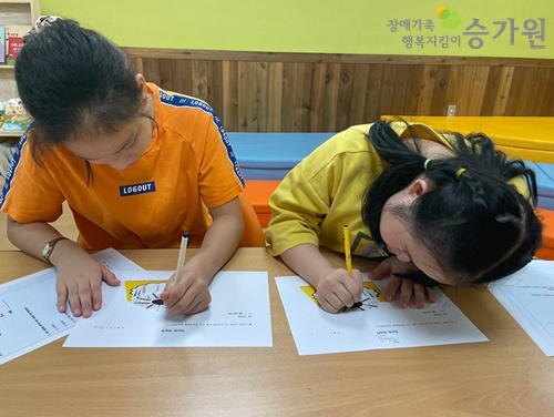 두 명의 여성 장애가족들이 책상에 앉아 색연필을 이용해 색칠공부를 이용한 성인지교육을 받고 있다. 장애가족행복지킴이 CI,