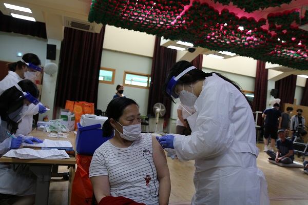 자비복지타운 강당에서 한 이용인이 한쪽 팔을 걷고 백신을 접종하고 있는 모습