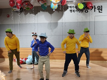 5명의 장애아동들이 알록달록 재밌는 모자를 쓰고 춤을 추고 있는 사진.천장에는 알록달록한 크리스마스 풍선이 매달려 있다. 우측 상단에 장애가족행복지킴이승가원ci 삽입.