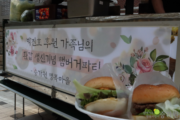 CI 삽입 장애가족 행복지킴이 승가원, 박진호 후원가족님의 환갑 생신기념 햄버거파티가 적혀져있는 햄버거 트럭앞에서 찍은 맛있는 햄버거 사진