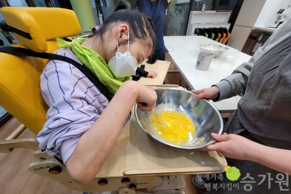장애가족행복지킴이 승가원ci 삽입 / 장애아동이 근무가족의 도움을 받아 계란 노란자를 풀고 있는 모습