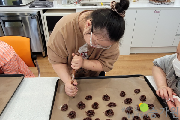 장애가족행복지킴이 승가원ci 삽입 / 여자 장애아동이 오븐용 팬에 초코쿠키를 만드는 반죽을 짤주머니로 짜고 있는 모습