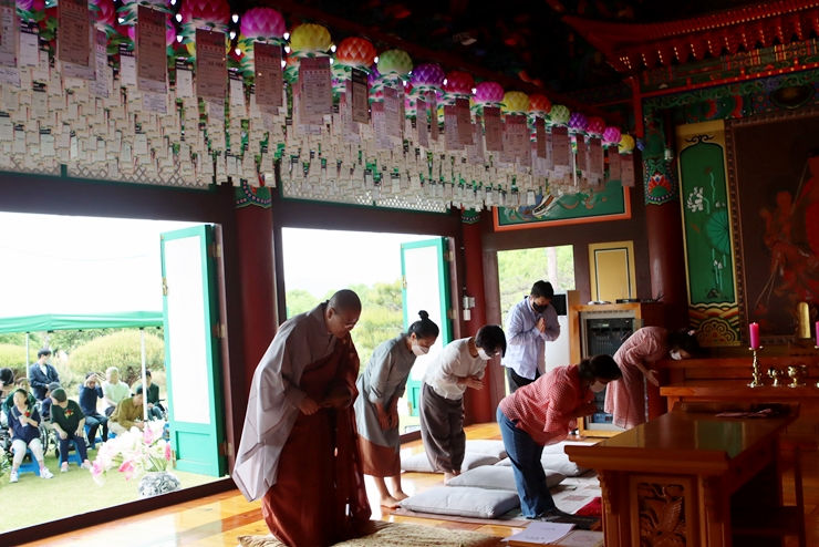 부처님 전에 1명의 스님과 5명의 불자님이 기도를 드리고 있는 사진