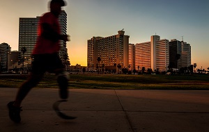 의족을 착용한 사람이 달리기를 하고 있는 사진. 배경으로 노을 지는 하늘 아래 4개의 높은 건물들과 나무들이 멀리 떨어져 보인다. 