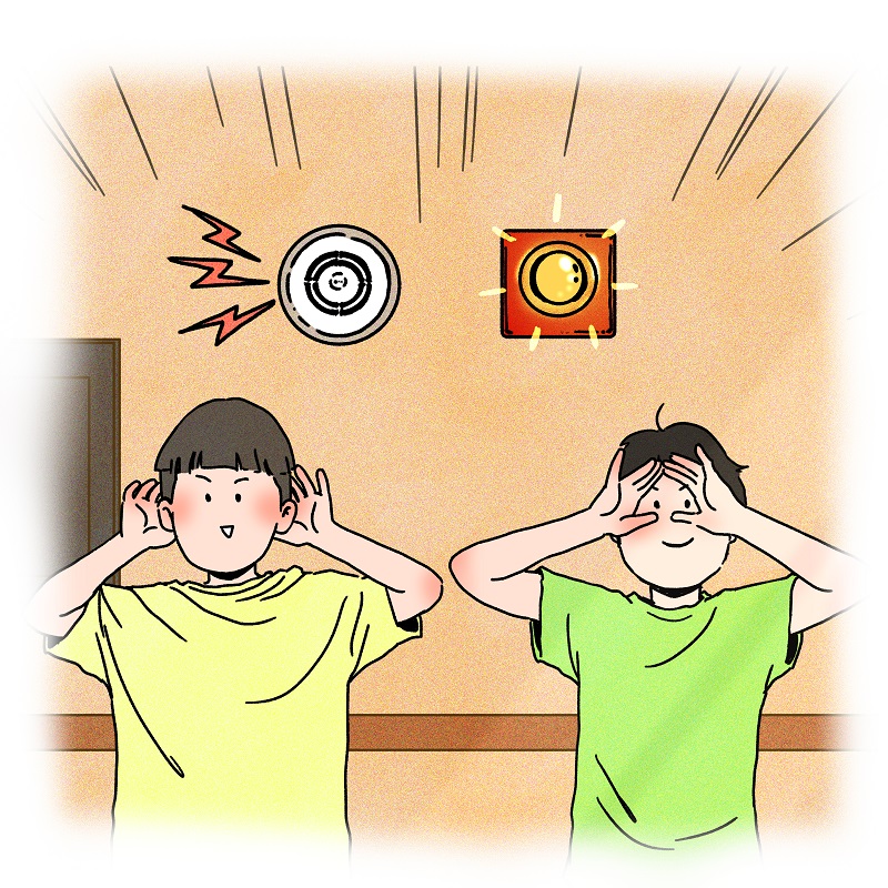 시청각경보기 아래에서 양쪽 귀에 손을 대고 소리를 듣는 남자아이, 양쪽 눈에 손을 대고 보는 모습을 표현하는 남자아이가 한명씩 서있다.