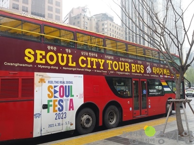 빨간색 2층 버스가 세워져 있고 ‘SEOUL CITY TOUR BUS, 타이거 버스라고 써져 있고 아랫 면에 흰 바탕에 ‘SEOUL FESTA 2023’라고 써져 있다. 오른쪽 하단 장애가족 행복지킴이 승가원CI