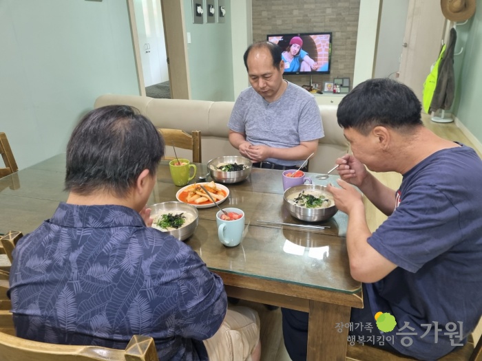 3명의 남성참여자가 식탁 앞에 앉아 식사를 하고 있다. 식탁 위에는 직접 만든 떡만둣국과 김치, 잘린토마토가 올라와있다.