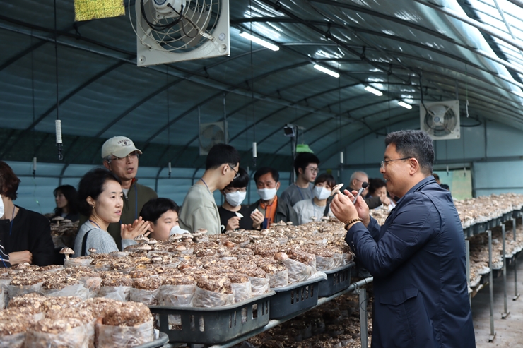 happy햇비장애인보호작업장의 버섯재배사에서 소홍문센터장의 설명을 듣고 있는 후원가족들의 모습