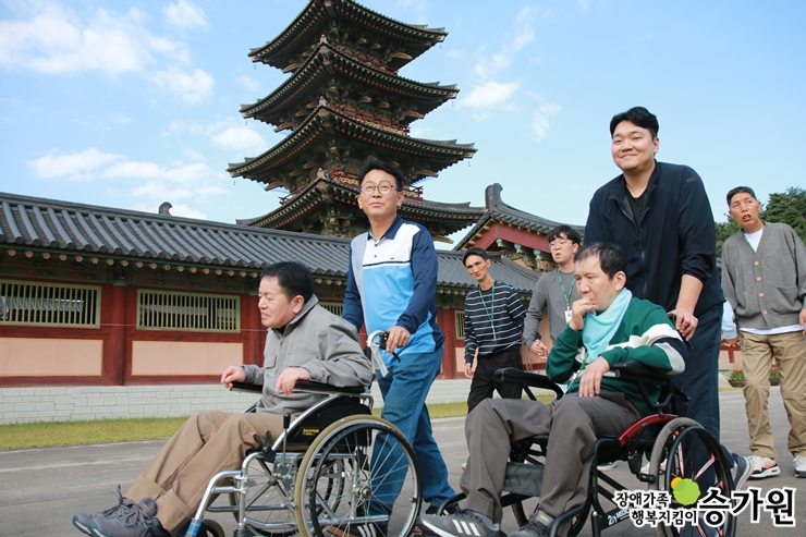 장애가족들이 휠체어를 타고 관광지를 둘러보고 있는 모습, 장애가족 행복지킴이 승가원ci 삽입