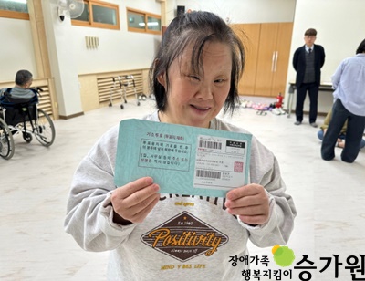 승가원 여성장애가족이 선거투표봉투를 두손으로 들고, 웃고 있는 모습, 오른쪽 아래 장애가족 행복지킴이 승가원 CI